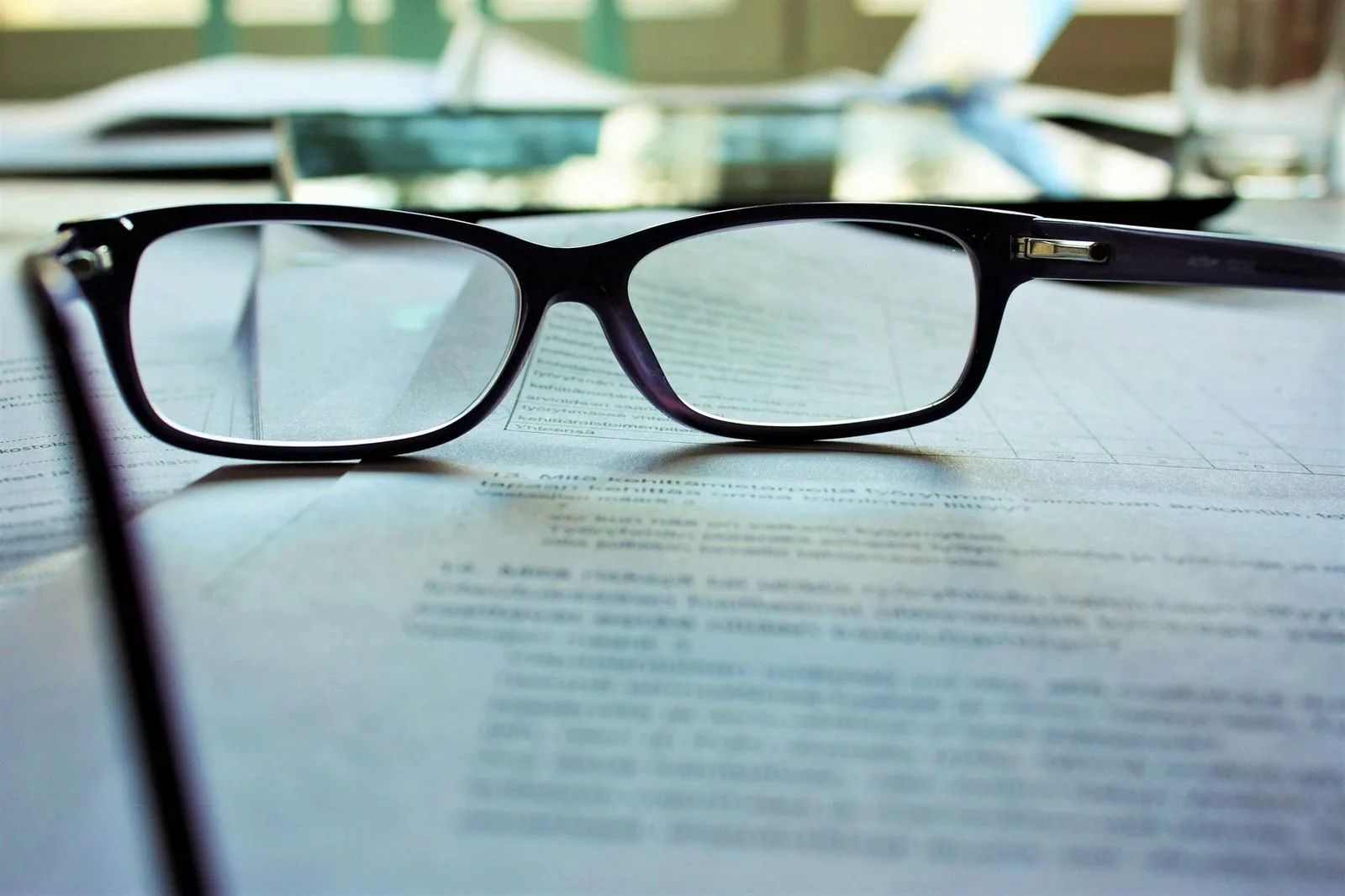 A pair of reading glasses resting on a printed policy document