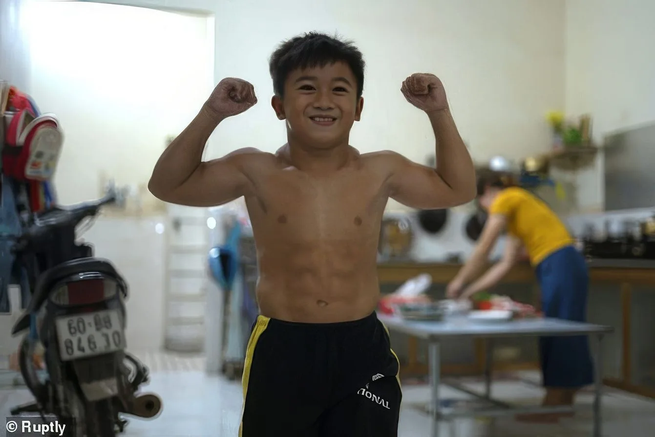 Nguyen Hoang Nam, a heavily muscled ten-year-old boy, flexing