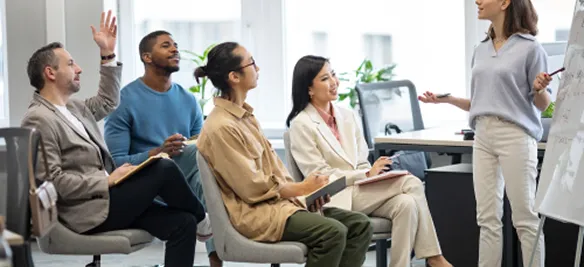 A team in a workshop, one person with a hand raised