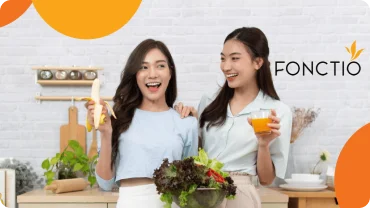 Two women with fresh salad and juice in a kitchen, with the Fonctio logo