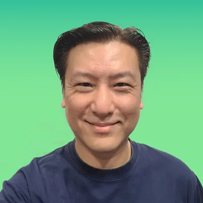 Cedric Lee smiling, in a navy top against a green background